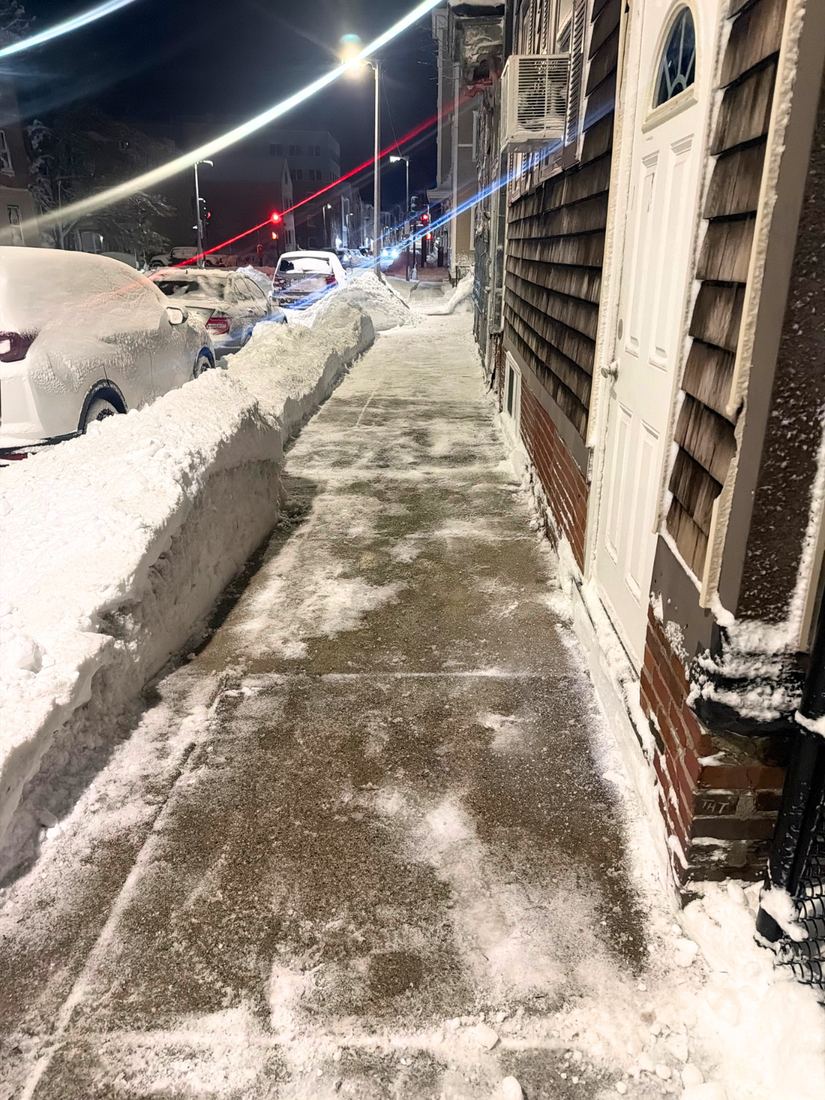 Cleared sidewalk along a residential street at night